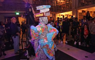 A performer wearing a suit made of maps and newspaper