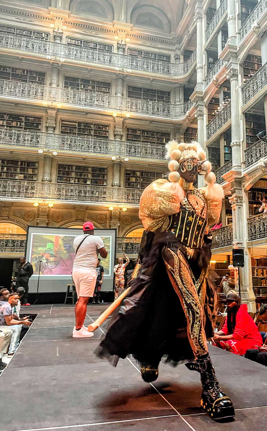 A performer in a futuristic costume on the stage at the George Peabody Library