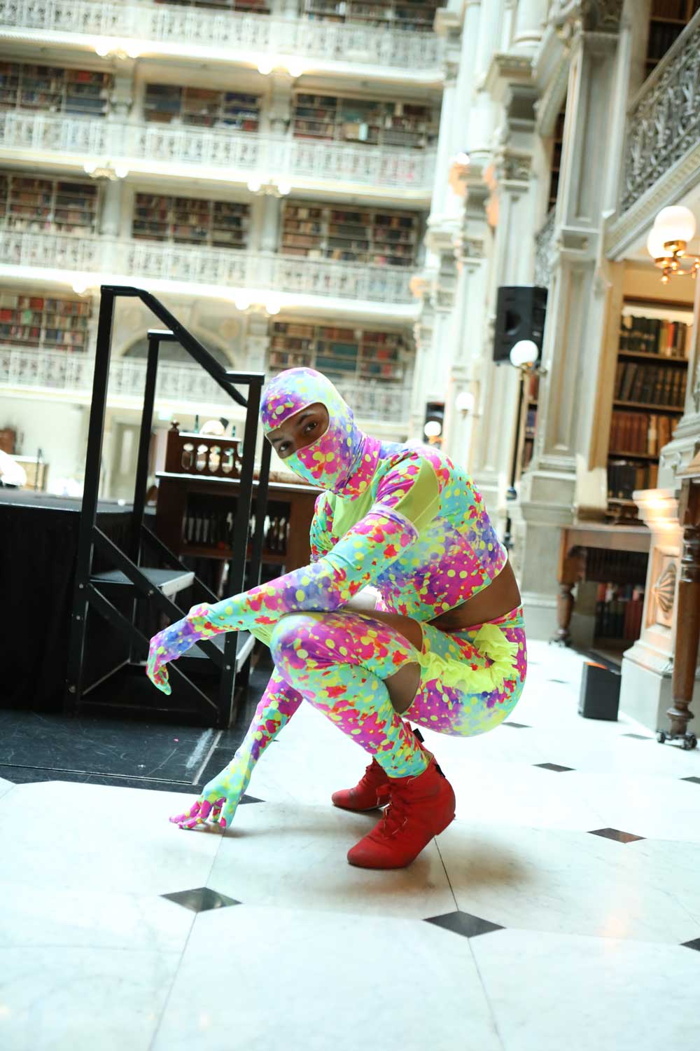 A person crouches near the stage at the George Peabody Library