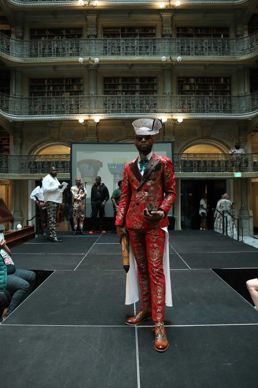 A performer in a red costume on the stage at the George Peabody Library